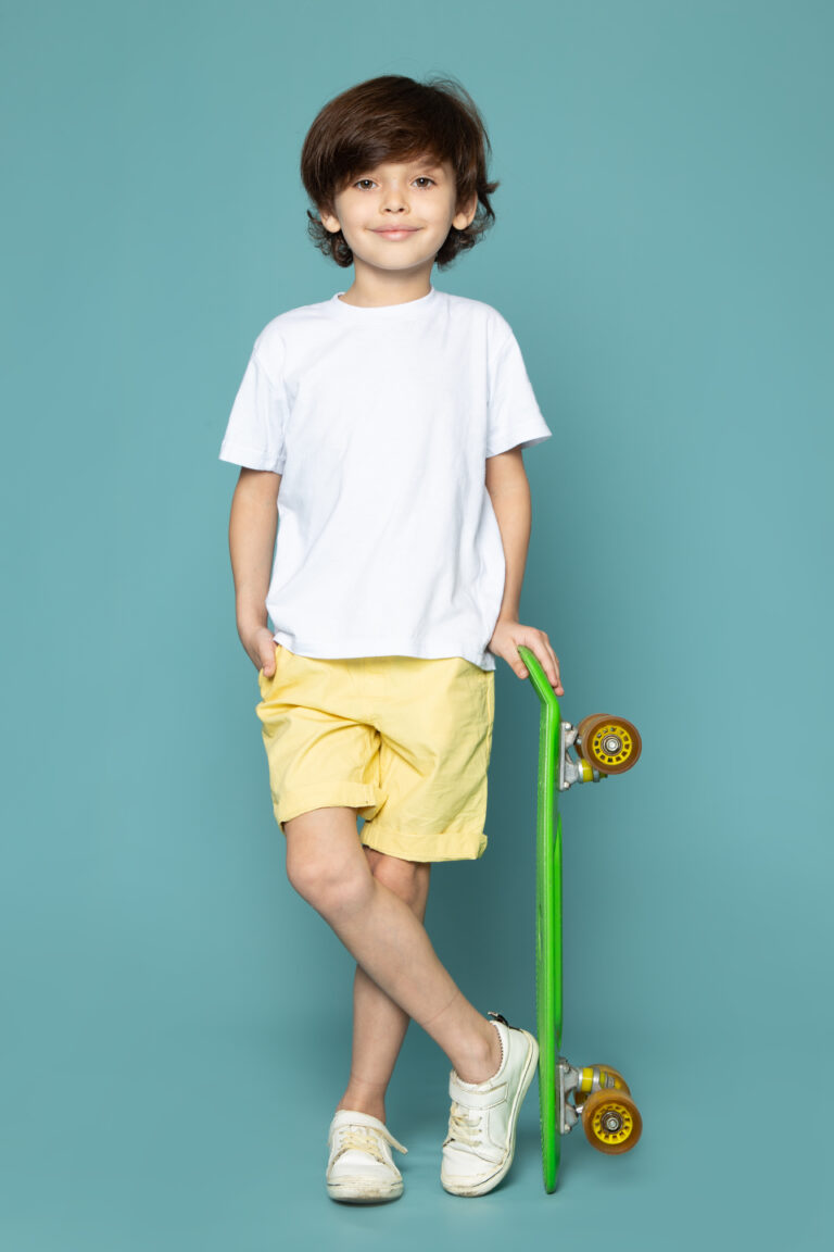 front-view-cute-child-boy-white-t-shirt-yellow-jeans-holding-green-skateboard-blue-floor